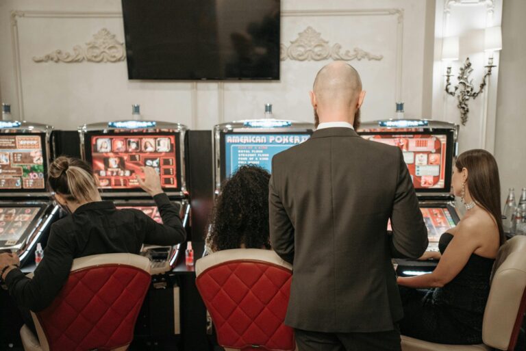 A group of adults engaged in playing slot machines inside a stylish casino setting.